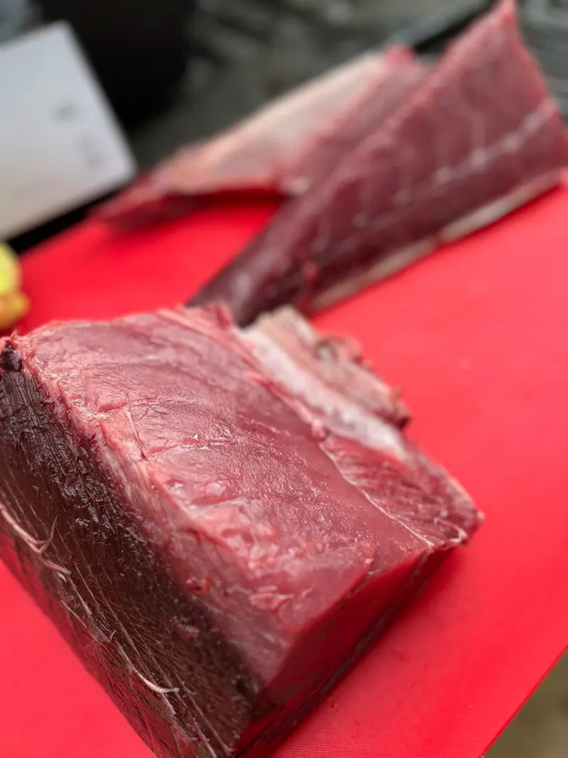 A fresh loin of ahi tuna on a red cutting board