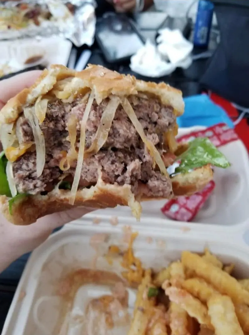 A double burger with melted cheese, grilled onions and lettuce, with crinkle-cut fries