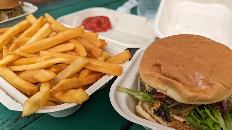 A burger with lettuce and fries in a takeout box from the Ae’s burger truck in Hāna