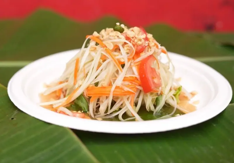 Green papaya salad with tomato, carrot and crushed peanuts on a banana leaf