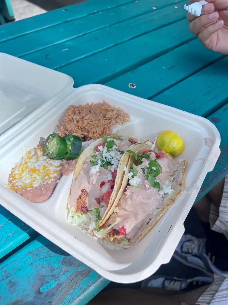 A taco plate with rice and beans on a teal picnic table