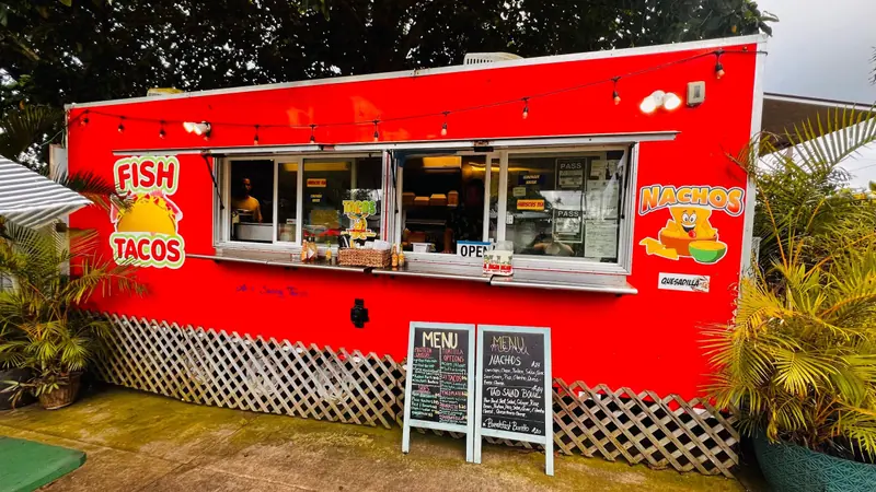 The red Ae’s Sassy Tacos trailer in Hāna with FISH TACOS painted on the side and chalkboard menus out front