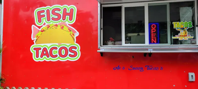 The truck window with Ae’s Sassy Tacos lettered in blue script under the FISH TACOS art